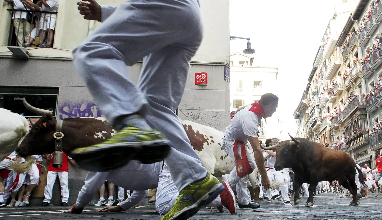 Para peserta berhamburan menyelamatkan diri dari serbuan banteng yang berlari liar di tengah kota saat Festival San Fermin Pamplona, Spanyol, Selasa (7/7/2015). (Reuters/Susana Vera)