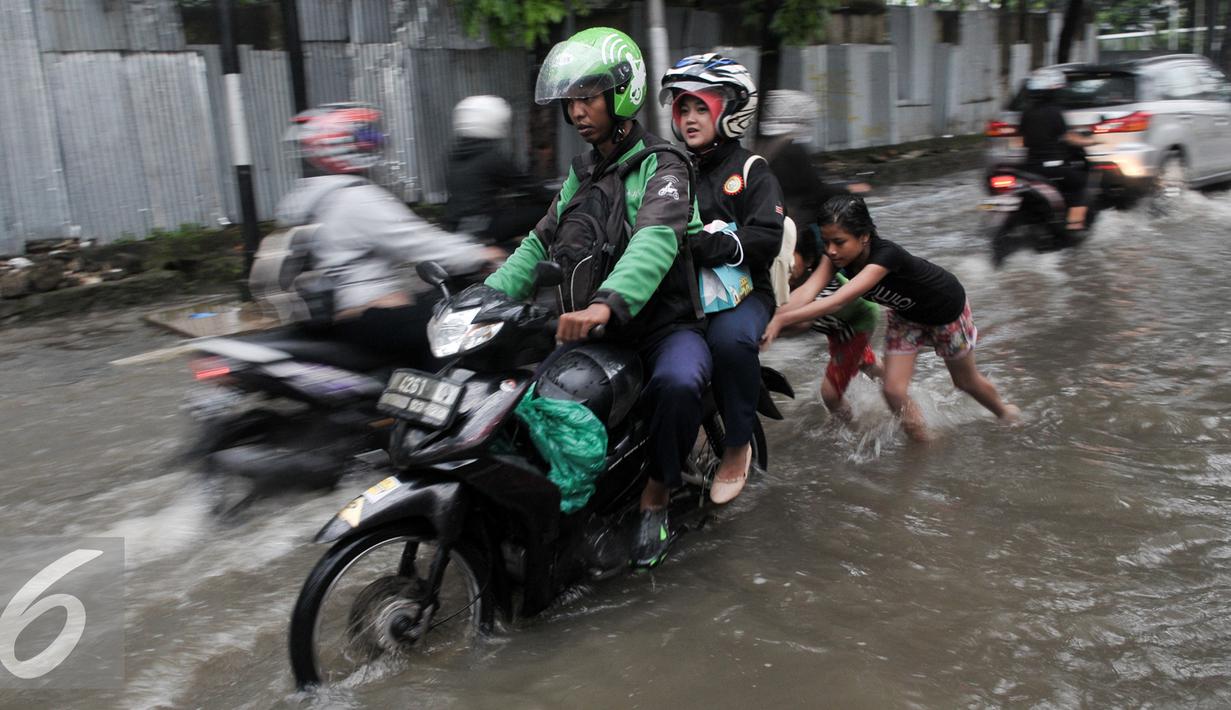 Sejumlah anak membantu pengendara motor yang mogok akibat menerobos genangan air di Pejaten Raya, Jakarta, Selasa (4/10). Akibat curah hujan yang tinggi menyebabkan sejumlah titik di Jakarta Selatan tergenang air. (Liputan6.com/Yoppy Renato)
