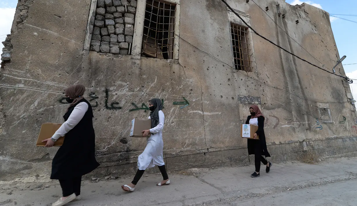 Sejulmah wanita dari Relawan Irak di asosiasi lokal saat mendistribusikan jatah makanan ke rumah tangga selama bulan Muslim Ramadhan di kota Mosul utara (7/5/2021). (AFP Photo/Zaid AL-Obeidi)