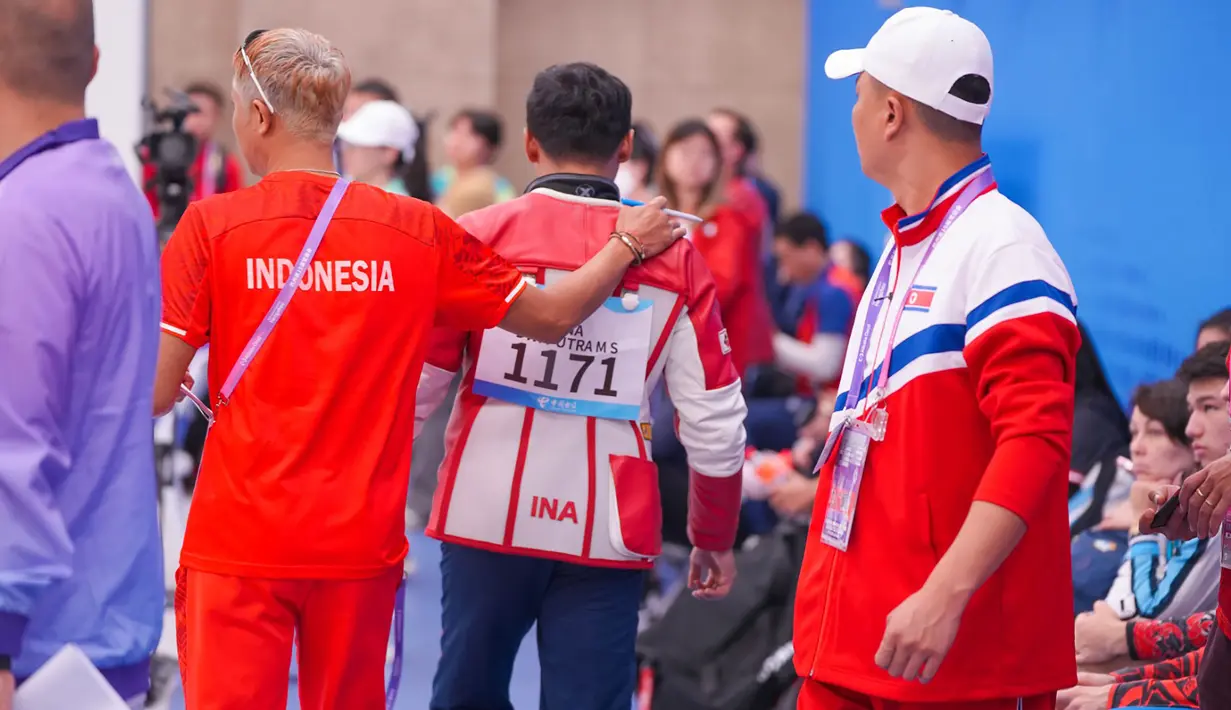 Petembak Indonesia, Muhammad Sejahtera Dwi Putra didampingi ofisial tim usai memenangi lomba nomor perorangan 10 meter running target putra cabang menembak Asian Games Hangzhou 2022 di Fuyang Yinhu Sports Centre, Hangzhou, China, Senin (25/9/2023). (NOC Indonesia)