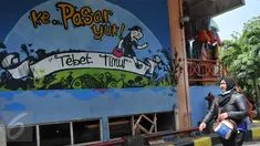Pengunjung melintas di dekat lukisan mural di Pasar PSPT, Tebet, Jakarta (14/11/2015). Keberadaan seni mural di pasar ini bisa membuat pengunjung tersenyum. (Liputan6.com/ Gempur M Surya)