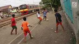 Kereta melintas di kawasan Kemayoran, Jakarta, Senin (24/7). Minimnya lahan bermain menyebabkan anak-anak terpaksa bermain di lokasi tersebut, meskipun berbahaya bagi keselamatan. (Liputan6.com/Immanuel Antonius)