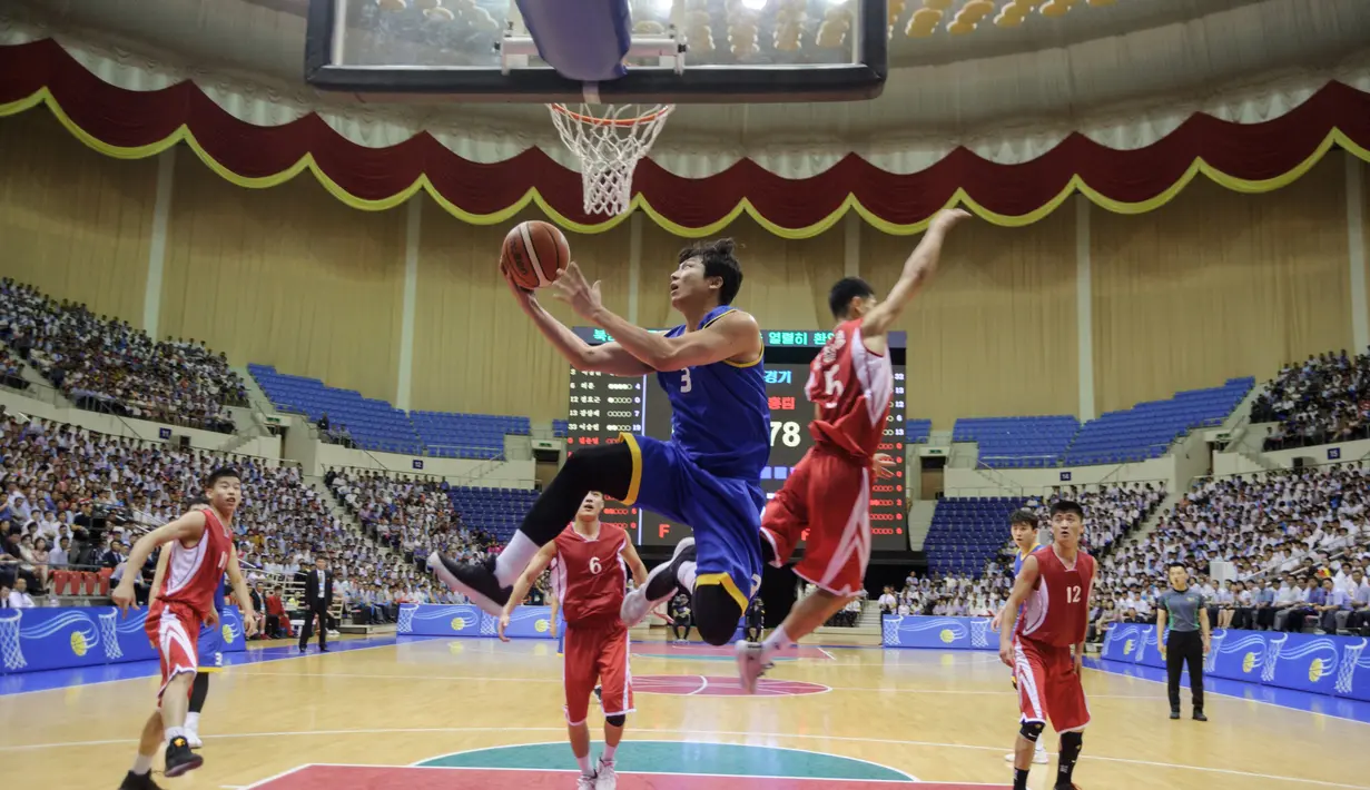 Pemain Korea Utara (merah) berusaha memblok bola dari serangan pemain Korea Selatan (biru) selama pertandingan basket pria ramah di Stadion Indoor Ryugyong Chung Ju-Yung, Pyongyang (5/7). Tim pria Korea Utara memenangkan 82-70. (AFP Photo/Kim Won-Jin)