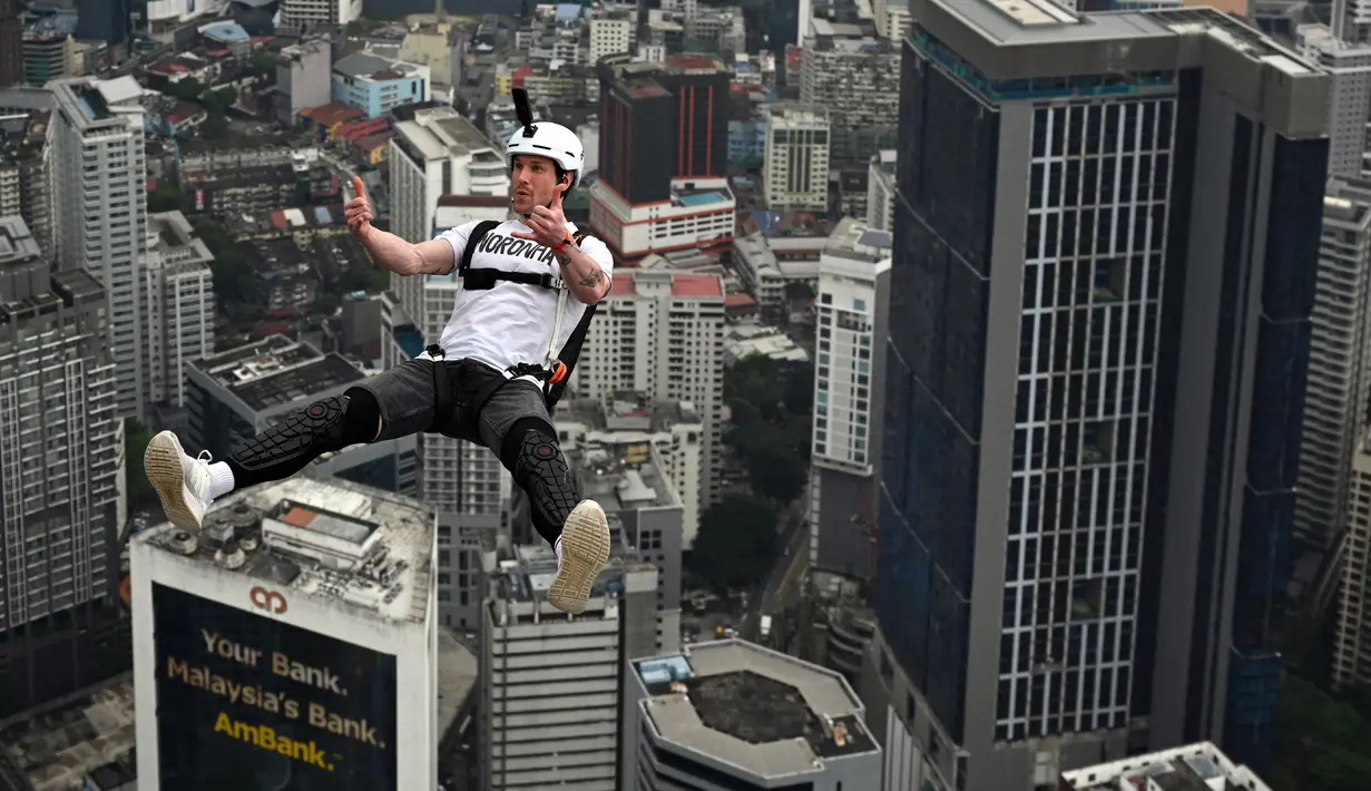 Penerjun Swiss Samuel Schumacher melompat dari dek terbuka Menara Kuala Lumpur saat International Tower Jump, Kuala Lumpur, Malaysia, 3 Februari 2023. Lebih dari 100 penerjun melompat dari Menara Kuala Lumpur setinggi 300 meter yang terkenal tersebut. (MOHD RASFAN/AFP)