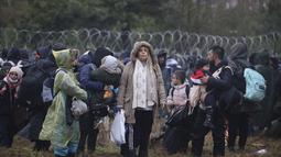 Migran dari Timur Tengah dan tempat lain berkumpul di perbatasan Belarus-Polandia dekat Grodno, Belarus, Senin (8/11/2021). Menurut pejabat setempat, Sekelompok besar migran masuk Belarusia tampaknya sedang berkumpul di sebuah titik penyeberangan. (Leonid Shcheglov/BelTA via AP)