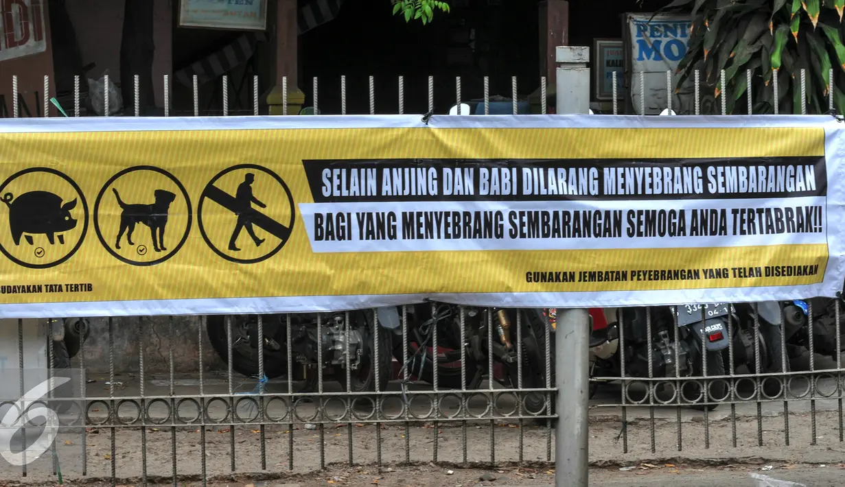 Spanduk himbauan untuk tidak menyeberang sembarang terpampang di pagar tempat warga biasa menyeberang di jalan raya Lenteng Agung, Jakarta, Kamis (3/12). (Liputan6.com/Yoppy Renato)