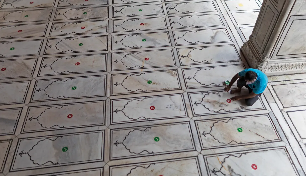 Pengurus menempelkan stiker di lantai bagi jemaah agar menjaga jarak selama salat ketika Masjid Jama dibuka kembali setelah pelonggaran lockdown di kawasan Kota Tua Delhi, Selasa (7/7/2020). India pada 6 Juli menjadi negara dengan jumlah virus corona tertinggi ketiga di dunia. (XAVIER GALIANA/AFP)