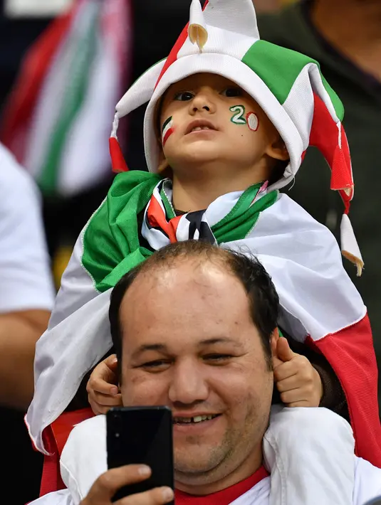 Seorang fans timnas iran mengendong anaknya sambil menyaksikan pertandingan Grup B Piala Dunia 2018 melawan Spanyol di Kazan Arena, Rusia, 20 Juni 2018. (AFP PHOTO / Roman Kruchinin)