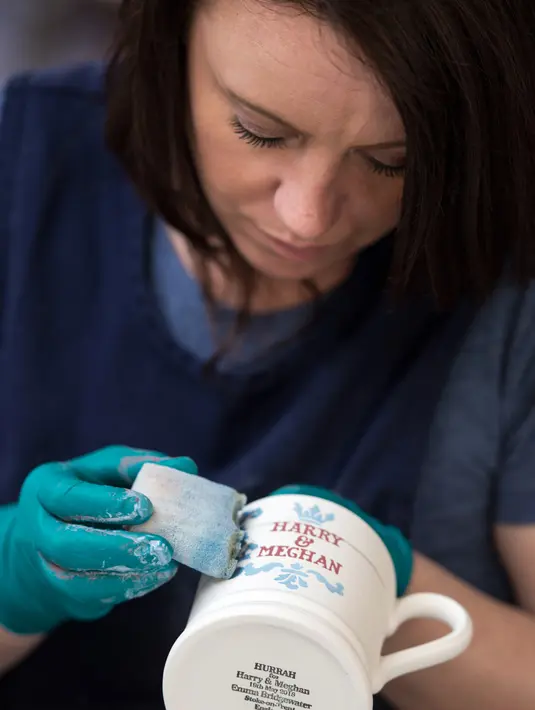 Seorang pekerja menyelesaikan pembuatan mug untuk merayakan pernikahan Pangeran Harry dan Meghan Markle di pabrik Emma Bridgewater di Stoke-on-Trent, Inggris (16/4). (AFP/Oli Scarff)