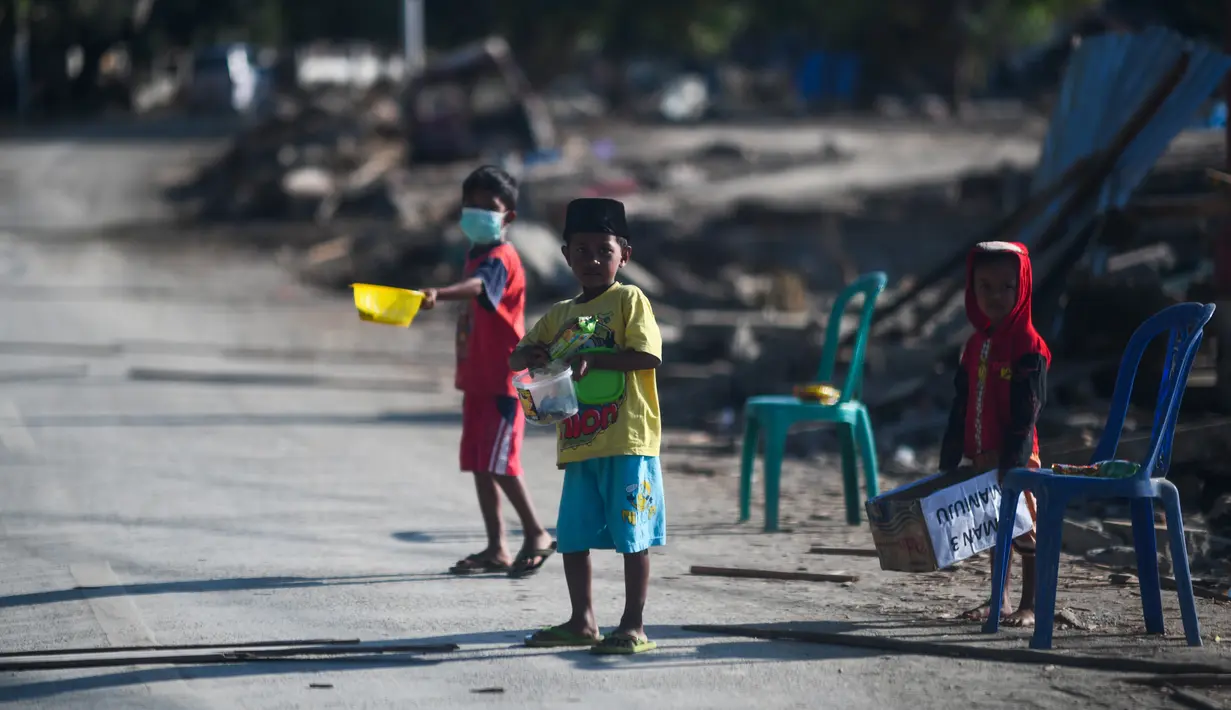 Anak-anak yang terkena dampak gempa meminta sumbangan pada pengguna jalan yang melintas di Donggala, Sulawesi Tengah, Jumat (5/10). Akibat terlambatnya pasokan bantuan, mereka terpaksa meminta sumbangan hingga turun ke jalan. (AFP PHOTO / Jewel SAMAD)
