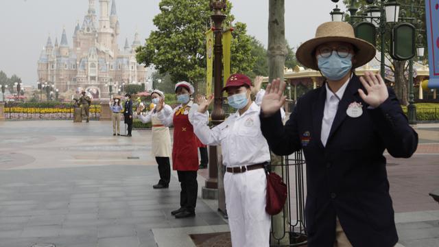 <span>Pegawai mengenakan masker saat menyambut wisatawan di taman hiburan Disneyland, Shanghai, China, Senin (11/5/2020). Disneyland Shanghai kembali dibuka setelah tiga bulan ditutup akibat pandemi virus corona COVID-19. (AP Photo/Chen Si)</span>