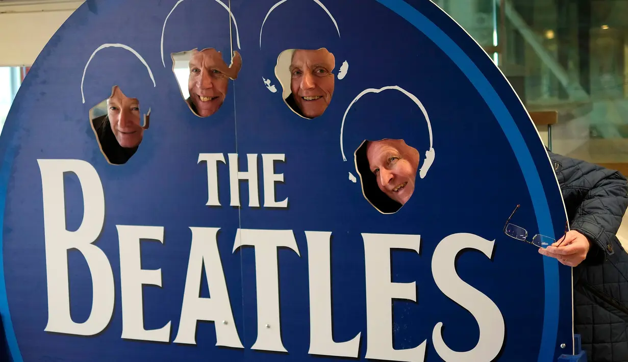 Wisatawan berpose disebuah papan Beatles di kafe kopi bertema The Beatles di Liverpool, , Inggris, (2/3). Warga Liverpool Peringati 50 tahun terakhir kali The Beatles melakukan konser di kota asal mereka ini. (REUTERS/Phil Noble)