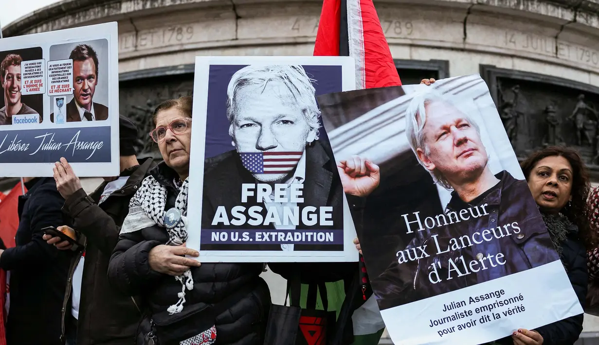 Para pengunjuk rasa memegang papan-papan saat unjuk rasa menuntut pembebasan pendiri Wikileaks, Julian Assange, di Place de la Republique, Paris, 20 Februari 2024. (Thomas SAMSON/AFP)