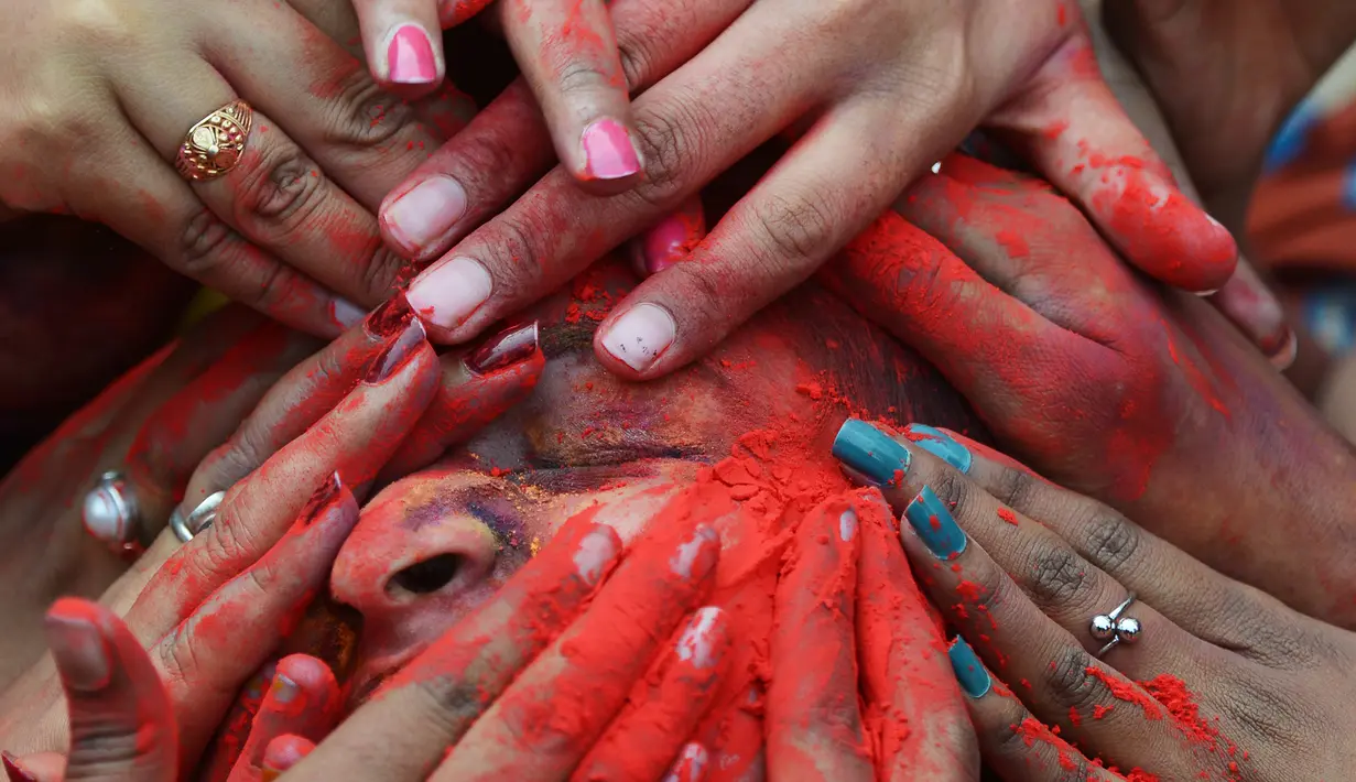 Wajah seorang siswa dilumurkan bubuk warna saat perayaan Holi di Kolkata, India (7/3). Holi atau Festival Warna adalah festival awal musim semi yang dirayakan di India, Nepal, Bangladesh, dan negara-negara yang mayoritas beragama Hindu. (AFP/Dibyangshu)