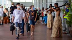 Penari tradisional dengan rok rumput menyambut wisatawan di Nadi, Fiji, Rabu (1/12/2021). Fiji membuka perbatasannya untuk pelancong internasional pertama kalinya sejak pandemi Covid-19 melanda dunia dan menghancurkan ekonominya yang bergantung pada pariwisata. (Leon LORD/AFP)