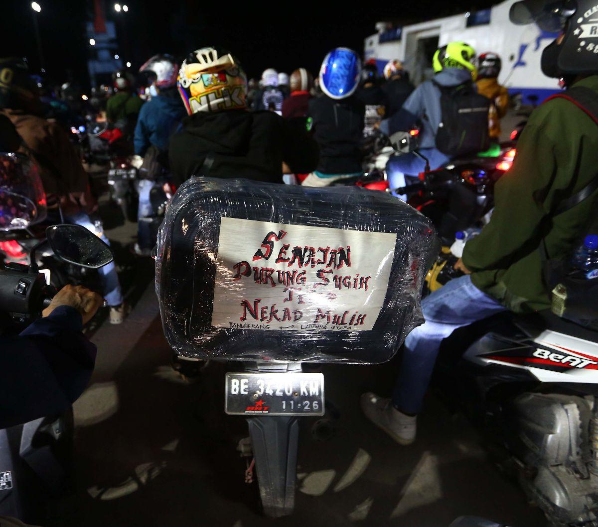 Sebuah tulisan terpasang pada bagian belakang sepeda motor pemudik di Pelabuhan Ciwandan, Cilegon, Banten, Sabtu (6/4/2024). Sejumlah pemudik menuliskan pesan-pesan unik bertema Lebaran yang dipasang di sepeda motornya. Liputan6.com/Angga Yuniar