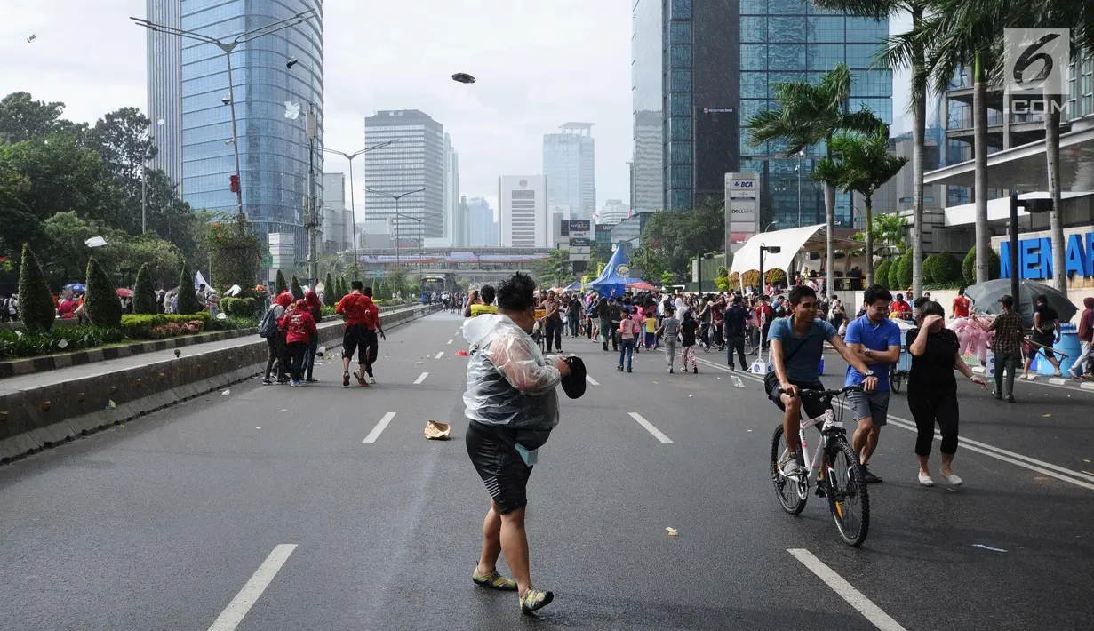 Warga menghindari hembusan angin kencang di sekitar Bundaran Hotel Indonesia, Jakarta, Minggu (26/11). Angin kencang dan gerimis terjadi saat kegiatan Hari Bebas Kendaraan, Minggu pagi. (Liputan6.com/Helmi Fithriansyah)