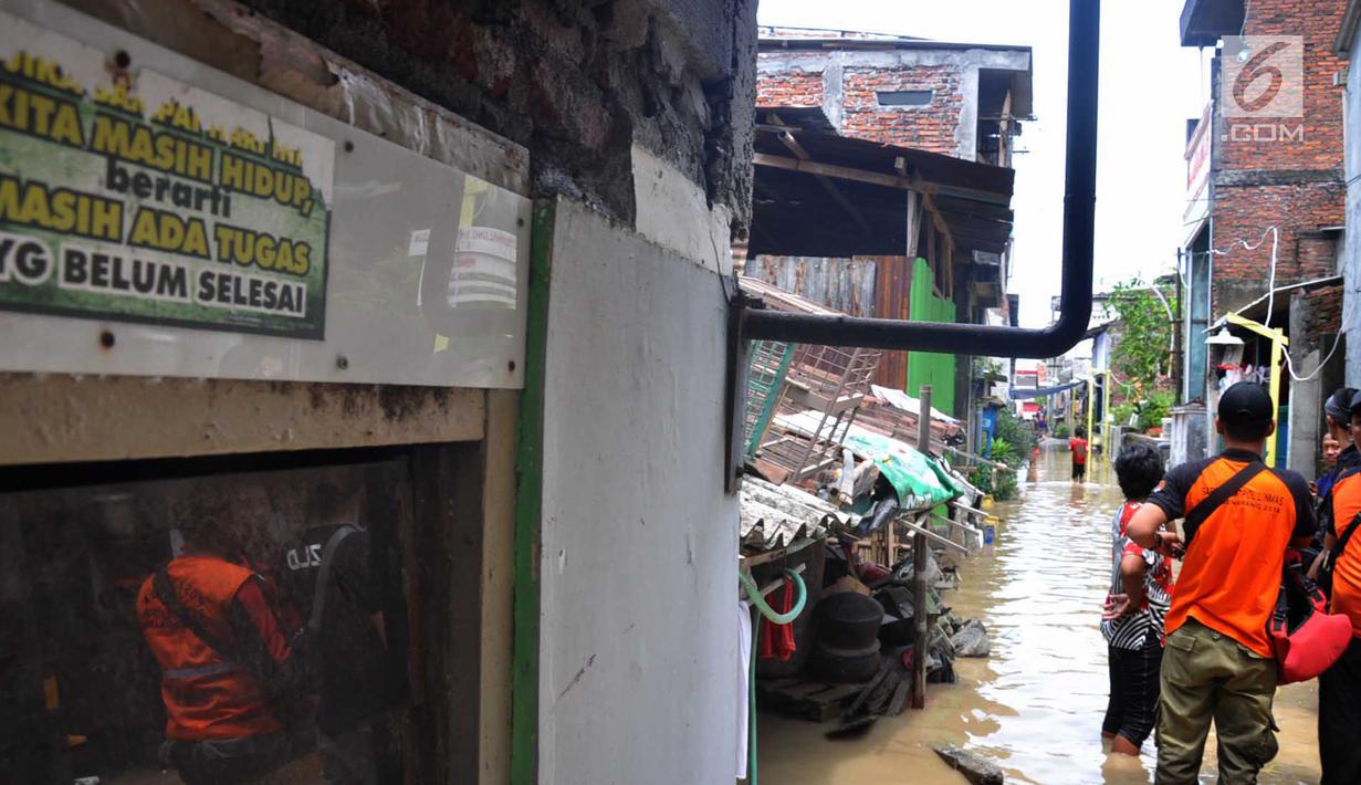 Petugas mengecek perumahan yang tergenang banjir di kawasan Sawah besar Semarang, Jawa Tengah, Sabtu (8/12). Tingginya curah hujan dan banyaknya tumpukan sampah diduga menjadi penyebab jebolnya tanggul. (Liputan6.com/Gholib)