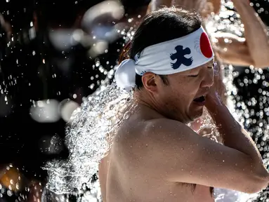 Seorang penganut agama Shinto menyiramkan air dingin ke tubuhnya di Kuil Kanda Myojin di Tokyo pada tanggal 13 Januari 2024. (Philip FONG/AFP)