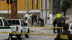 Polisi Kolombia dan ahli forensik memeriksa lokasi ledakan di dekat arena adu banteng Plaza Santamaria di pusat kota Bogota, Minggu (19/2). Sebagian besar korban adalah polisi yang tengah bertugas untuk mengamankan demonstrasi. (AP Photo/Ricardo Mazalan)