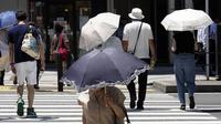Orang-orang berjalan di bawah sinar matahari di Tokyo, Jepang, 12 Juli 2023. Cuaca panas pada hari Rabu telah ditetapkan dengan suhu naik lebih dari 36 derajat Celcius (97 derajat Fahrenheit) di Tokyo, menurut Badan Meteorologi Jepang. (AP Photo/Eugene Hoshiko)