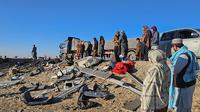 Warga Afghanistan memeriksa lokasi kecelakaan di dekat puing bus setelah bertabrakan dengan truk batu bara di jalan raya antara Kabul dan Kota Kandahar selatan, 19 Desember 2024. (AFP)