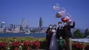 Sepasang suami istri mengambil foto pernikahan mereka dengan teman-teman sambil mengenakan masker pelindung untuk mencegah penyebaran virus corona di tepi pantai melawan Victoria Habour di Hong Kong (2/1/2021). (AP Photo/Vincent Yu)