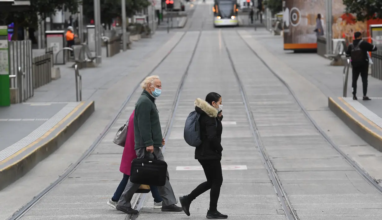 Orang-orang menyeberang jalan yang sepi di kawasan pusat bisnis Melbourne, Rabu (11/8/2021). Lima juta orang di kota terbesar kedua di Australia tersebut akan tetap berada di bawah perintah tinggal di rumah, setidaknya selama seminggu lagi. (William WEST/AFP)