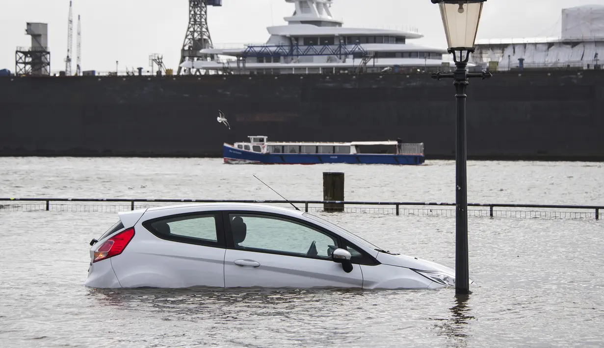 Sebuah mobil terendam air banjir setelah badai di Hamburg, Jerman, Minggu (30/1/2022).Badai musim dingin yang kuat melanda Eropa utara selama akhir pekan. (Daniel Bockwoldt/dpa via AP)