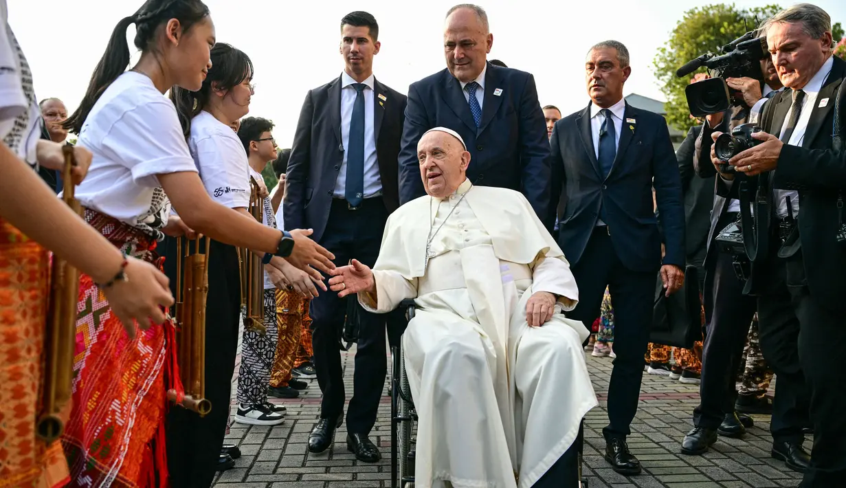 Sebelum masuk ke dalam, Paus Fransiskus berkeliling menemui sejumlah anak yang berdiri menjadi pagar betis menyambut kedatangannya. (Tiziana FABI/AFP)