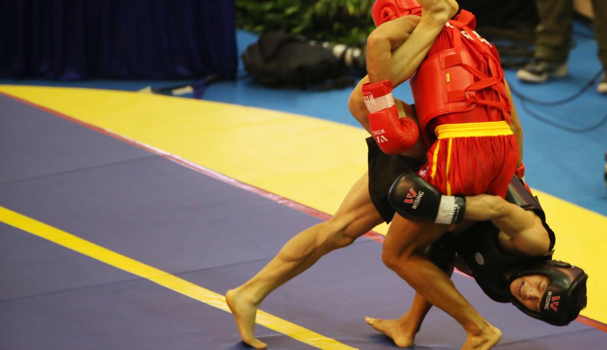 Atlet Wushu Indonesia, Gunawan (merah) membanting lawannya Man Kam Lam asal Hongkong pada Kejuaraan Dunia Wushu 2015 di Istora, Senayan, Jakarta, Sabtu(14/11/2015). (Bola.com/Nicklas Hanoatubun)