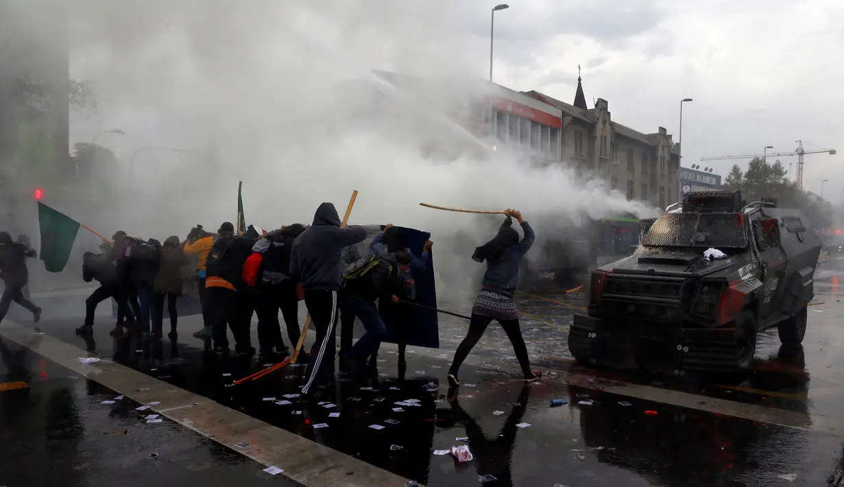 Bentrokan terjadi antara demonstran dan polisi anti huru hara selama peringatan May Day 2016 atau Hari Buruh Sedunia di Santiago, Chili, Minggu (1/5). Di beberapa negara, peringatan buruh sempat diwarnai dengan aksi bentrok. (REUTERS/Ivan Alvarado)