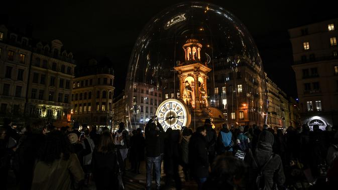 Orang-orang mengambil gambar sebuah monumen yang diterangi cahaya lampu selama festival cahaya, Fete De Lumiere, di Lyon, Prancis, Kamis (6/12). Selama festival, semua bangunan di kota tersebut menjadi karya seni luar biasa. (JEAN-PHILIPPE KSIAZEK / AFP)