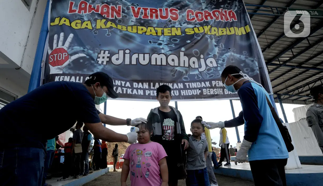 Petugas memeriksa suhu tubuh warga yang ingin menuju wilayah Sukabumi saat sterilisasi kendaraan di Terminal Cicurug, Sukabumi, Jawa Barat, Minggu (12/4/2020). Proses sterilisasi ini dilakukan untuk mencegah penyebaran virus corona COVID-19. (merdeka.com/Arie Basuki)