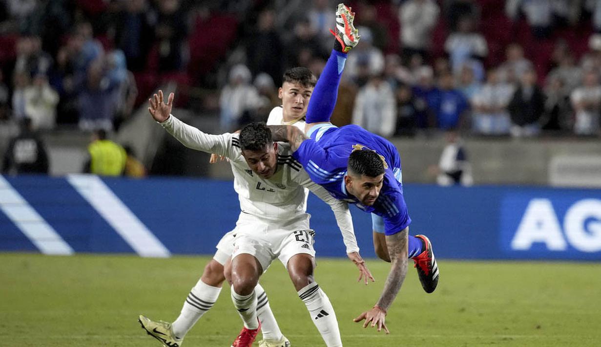 Pemain Argentina, Cristian Romero, terjatuh saat berebut bola dengan pemain Kosta Rika, Alvaro Zamora, dalam laga persahabatan yang digelar di Los Angeles Memorial Coliseum, Amerika Serikat, Rabu (27/3/2024). (AP Photo/Eric Thayer)