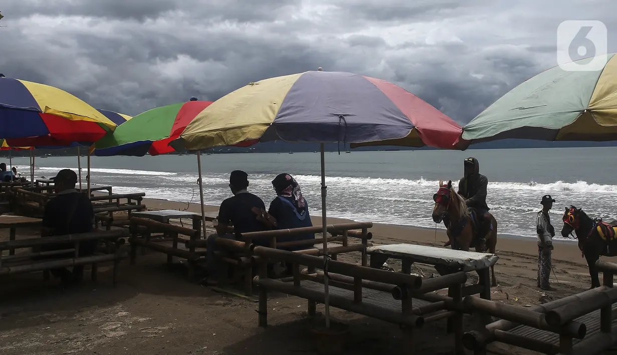 Warga bersantai di Pantai Pelabuhan Ratu, Kabupaten Sukabumi, Jawa Barat, Jumat (12/11/2021). Pantai Pelabuhan Ratu menjadi tempat wisata favorit warga Jawa Barat serta Jakarta dan sekitarnya. (Liputan6.com/Johan Tallo)