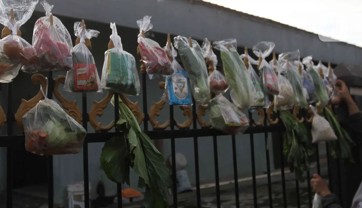 Sejumlah sayuran, beras, dan bumbu masak secara gratis yang digantung pada pagar rumah di Gang Palautan, Cilodong, Depok, Jumat (21/1/2022). Warga Rt 04 Rw 01 di kawasan tersebut secara swadaya berbagi setiap hari Jumat kepada warga yang terdampak pandemi COVID-19. (Liputan6.com/Herman Zakharia)