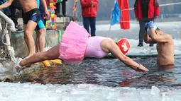 Seorang penggemar renang musim dingin menyelam ke danau yang sebagian beku di Shenyang, di provinsi Liaoning, China pada 25 Januari 2022. Berenang di musim dingin adalah kegiatan olahraga yang jarang dijumpai kecuali di beberapa negara dengan musim dingin yang cukup panjang. (STR/AFP)