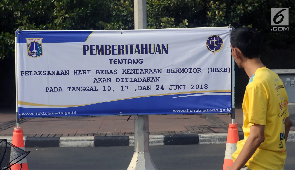 Warga melihat spanduk pemberitahuan peniadaan pelaksanaan Hari Bebas Kendaraan Bermotor (HBKB) di sekitar Bundaran Hotel Indonesia, Jakarta, Minggu (3/6). Pelaksanaan HBKB akan ditiadakan pada 10, 17, dan 24 Juni 2018. (Liputan6.com/Helmi Fithriansyah)