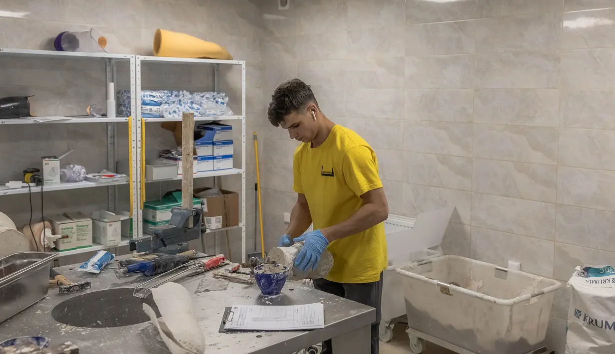 Seorang karyawan sedang bekerja untuk membuat prostesis di Pusat Rehabilitasi Nasional Unbroken di Lviv, Ukraina barat, pada 18 September 2023. (Roman PILIPEY/AFP)