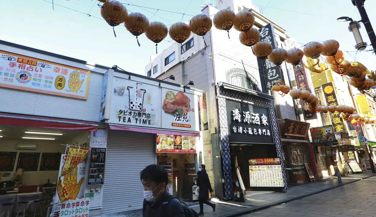 Orang-orang yang memakai masker berjalan di bawah pernak-pernik Imlek saat melintasi Chinatown di Yokohama, Prefektur Kanagawa, dekat Tokyo, Selasa (9/2/2021). Yokohama Chinatown adalah kawasan pecinan terbesar di Jepang, terletak di pusat kota Yokohama. (AP Photo/Koji Sasahara)