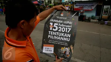 Seorang warga membaca poster yang dibagikan oleh KPU saat sosialisasi Pilkada DKI 2017 di Terminal Senen, Jakarta, Minggu (18/12). Sosialisasi pesta demokrasi ini guna mencegah banyaknya pemilih yang golongan putih atau golput. (Liputan6.com/Johan Tallo)