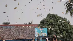 Para murid saling berebut hujan uang di lapangan SMP Angkasa Halim Perdana Kusuma, Jakarta, Kamis (7/6). Hujan uang ini dalam rangka pre-launching buku milik motivator bisnis Tung Desem Waringin berjudul "LIFE REVOLUTION." (Liputan6.com/Faizal Fanani)