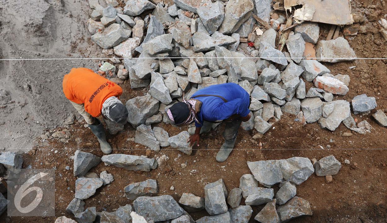 Pekerja memasang batu membuat pondasi turap jalan dalam pengerjaan proyek penataan ulang Kalijodo, Jakarta (18/3). Pengerjaan di sepanjang Jalan Kepanduan II, mulai dari ujung di Jalan Teluk Gong, hingga Jalan Tubagus Angke. (Liputan6.com/Gempur M Surya)