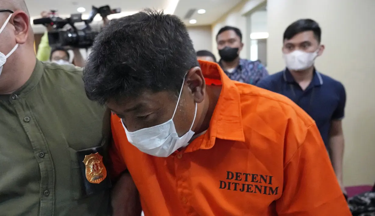 Mitsuhiro Taniguchi (47) dikawal petugas imigrasi usai konferensi pers di Kantor Imigrasi, Jakarta, Indonesia, Rabu (8/6/2022). Kepala Divisi Humas Polri Irjen Dedi Prasetyo mengatakan Mitsuhiro Taniguchi ditangkap di Kalirejo, Lampung Tengah. (AP Photo/Achmad Ibrahim)