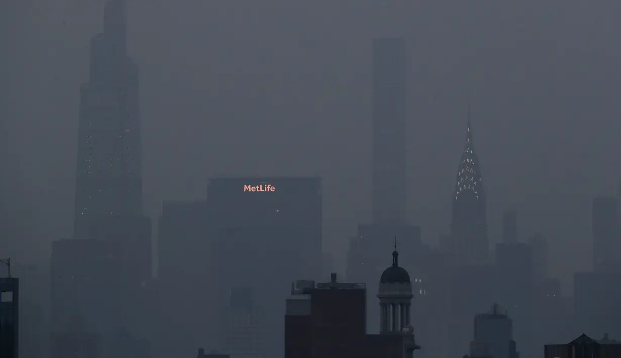 Bangunan Met Life dan Chrysler bersinar melalui kabut tebal yang menggantung di langit Manhattan, New York, Selasa (20/7/2021). Lebih dari 60 kebakaran hutan melanda sekitar 10 negara bagian di barat Amerika Serikat (AS), menyebabkan langit berkabut hingga New York.  (AP Photo/Julie Jacobson)