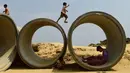 Anak-anak pengungsi Rohingya bermain dan berlarian di atas pipa limbah di kamp pengungsi Kutupalong, Bangladesh (5/4). Pemerintah Bangladesh mengatakan akan memulai relokasi sekitar 100.000 pengungsi Rohingya. (AFP Photo/Munir Uz Zaman)