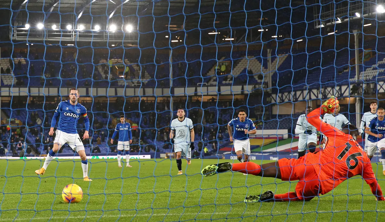 Gelandang Everton, Gylfi Sigurdsson (kiri), mengecoh Kiper Chelsea, Edouard Mendy untuk mencetak gol lewat eksekusi penalti dalam laga lanjutan Liga Inggris 2020/21 pekan ke-12 di Goodison Park Stadium, Sabtu (12/12/2020). Everton menang 1-0 atas Chelsea. (AFP/Clive Brunskill/Pool)