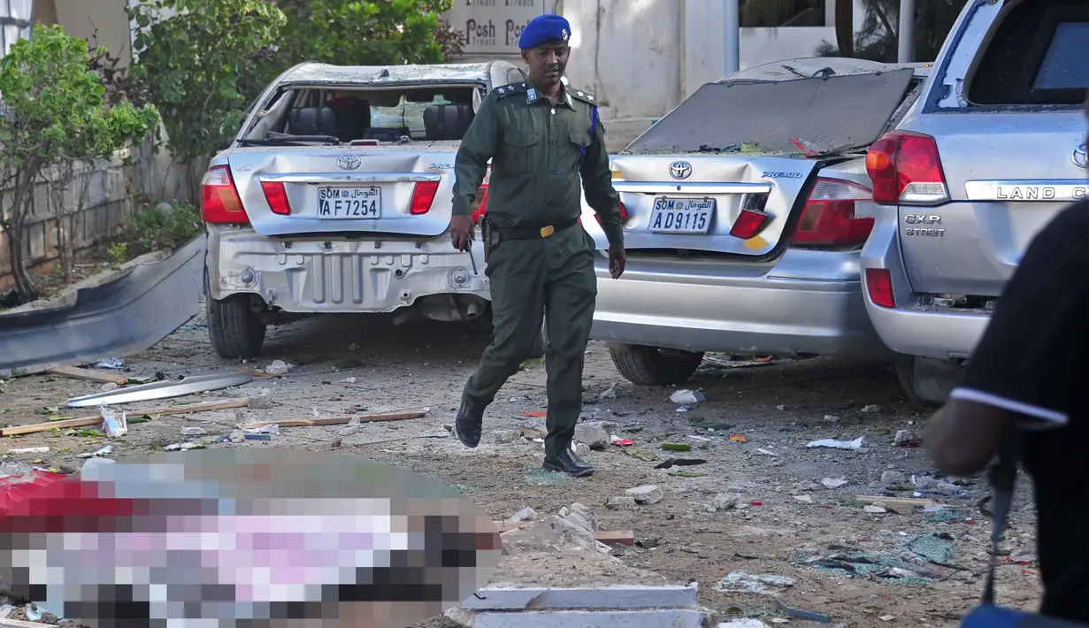 Petugas berjalan di dekat jenazah korban serangan bom bunuh diri di di Mogadishu, Somalia, Kamis (15/6). Kelompok Al-Shabaab mengaku bertanggung jawab atas serangan tersebut. (AFP Photo)