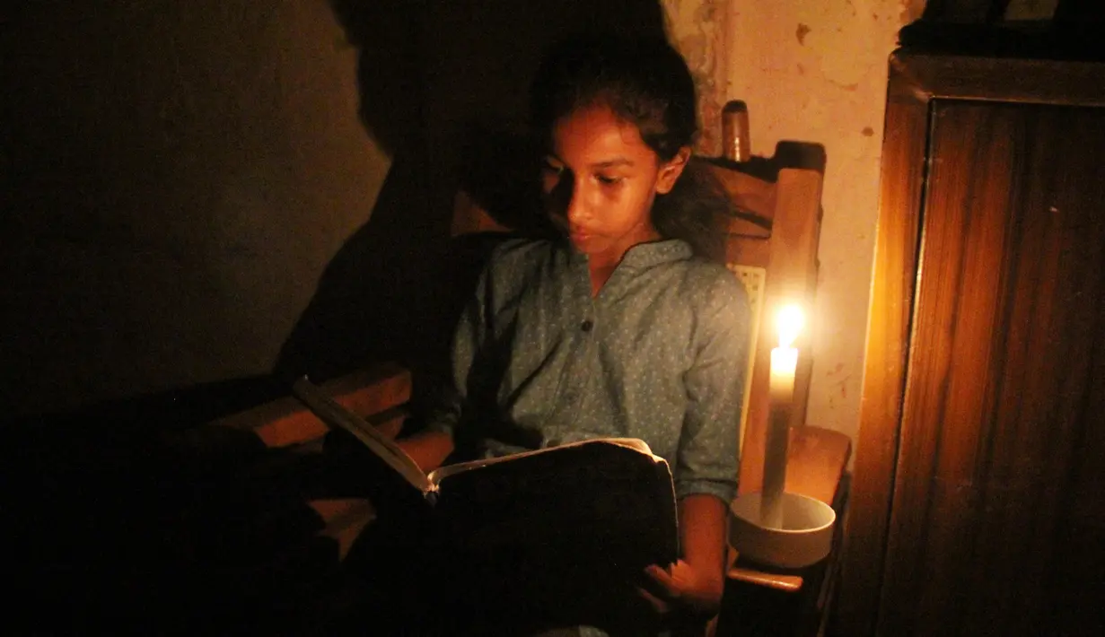 Seorang gadis membaca dengan bantuan lilin di tengah pemadaman listrik di Kolombo, Sri Lanka (17/8/2020). Sri Lanka mengalami pemadaman listrik berskala nasional pada Senin (17/8) karena kerusakan teknis di sebuah pembangkit listrik di Kerawalapitiya. (Xinhua/A. Hapuarachchi)
